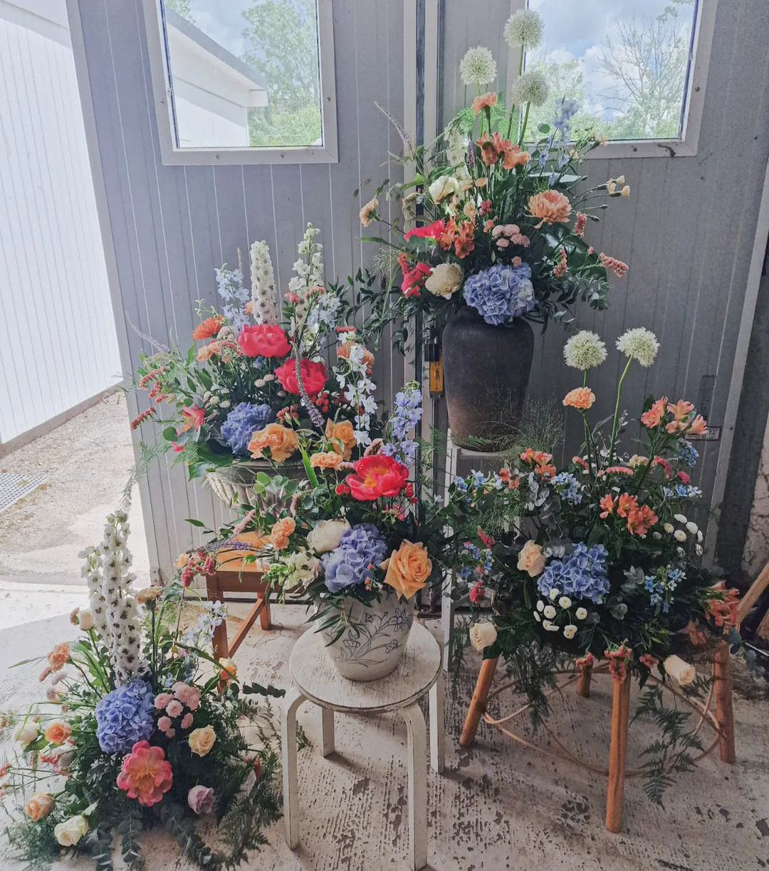 Fyra blombuketter med röda, gröna, oranga och lila blommor på stolar