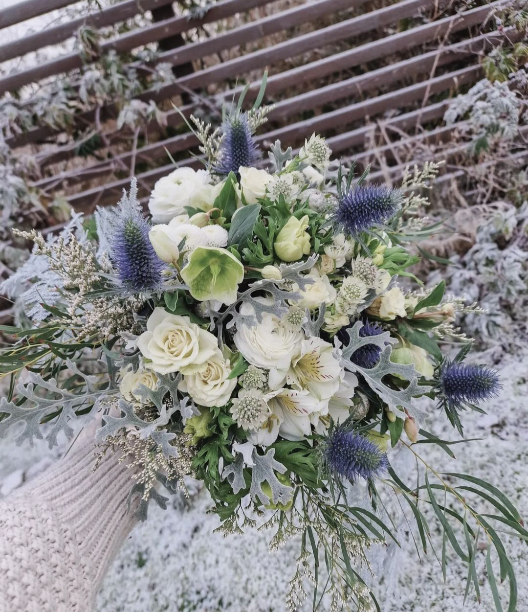 Blombukett med vita, gröna och lila blommor i snön