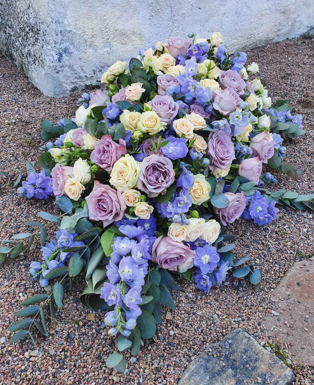 Stor Blombukett liggandes på en grus plan med gröna, rosa, lila och gula blommor 